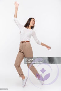 Full length portrait of a laughing asian businesswoman standing on tiptoes isolated over white background